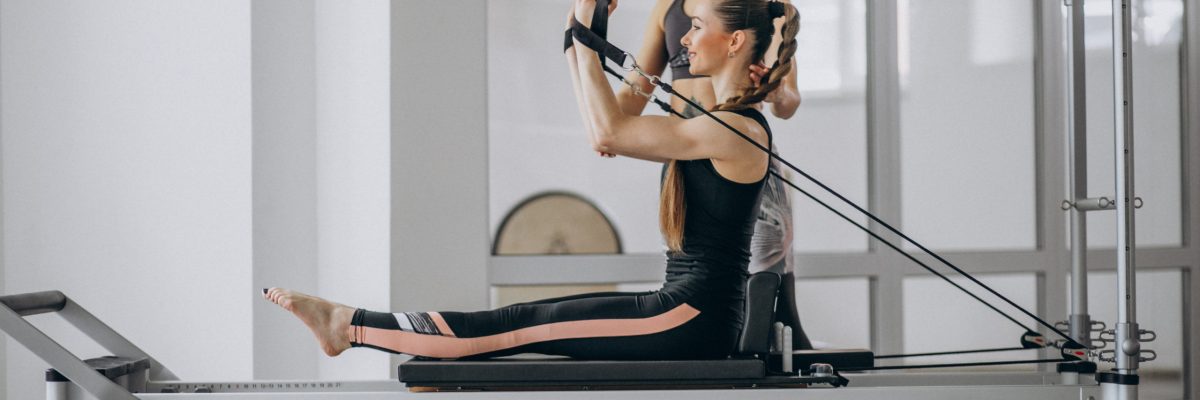 Woman with pilates trainer practising pilates